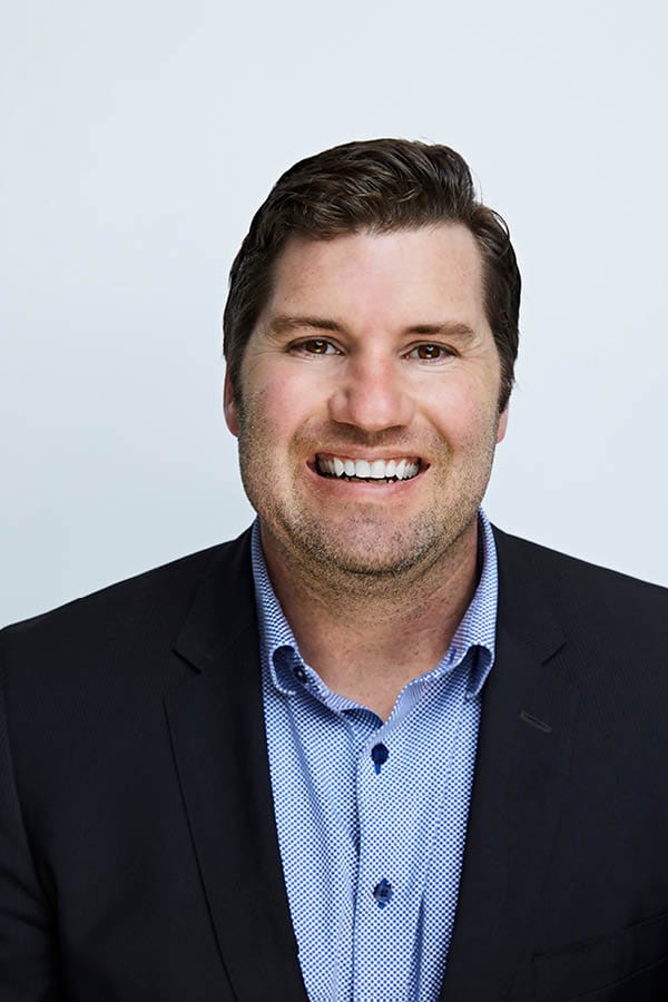 smiling businessman in suit headshot Smiling man in a business suit with a light blue shirt on a plain background